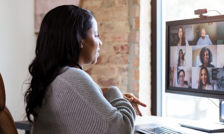 A woman at her home desk on a video call with her coworkers