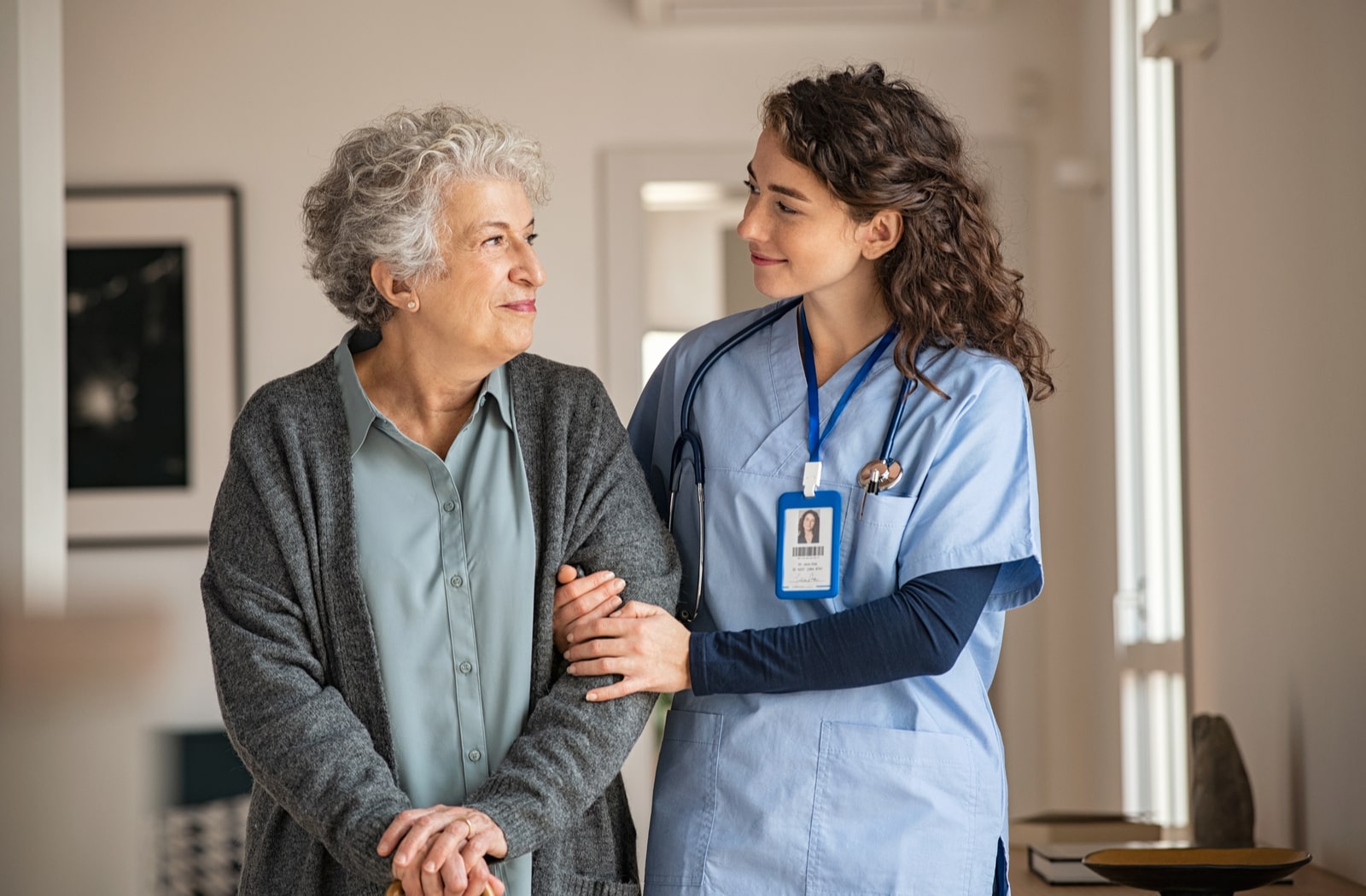 A female nurse walking with a female senior citizen patient in an assisted living home