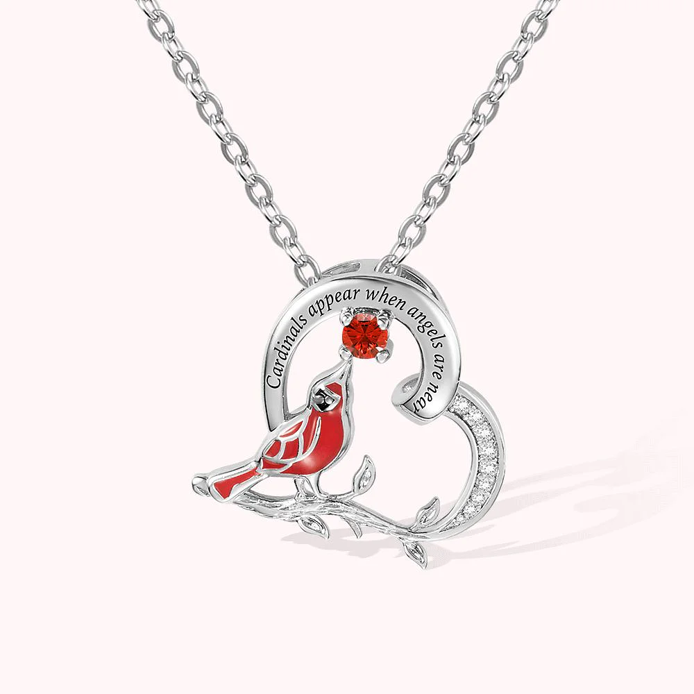 collier en forme de cœur formant une branche sur laquelle est posé un oiseau cardinal touchant du bec un rubis laissant penser à une rose.