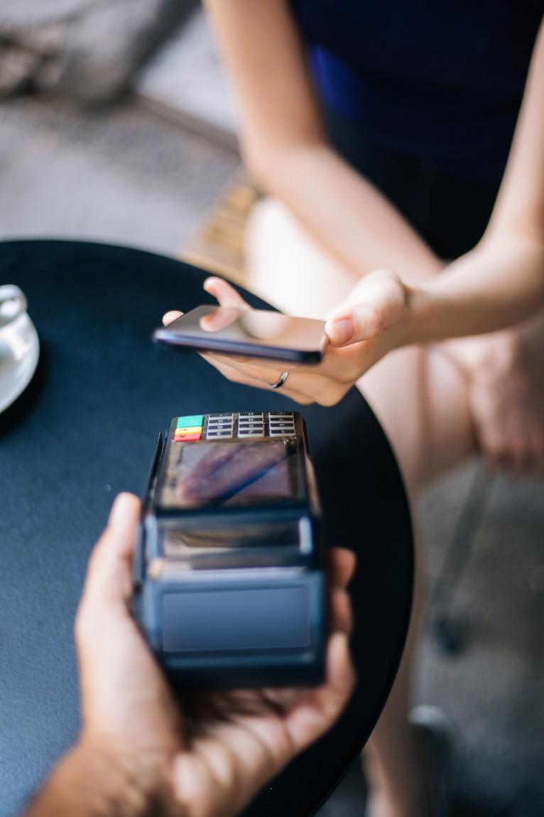 Person paying with a contactless POS system with their smartphone use at restaurants looking to improve customer safety.