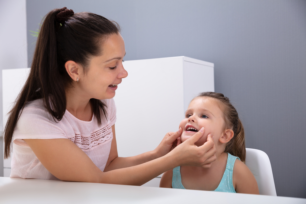 Parent helping girl to pronounce vowels 