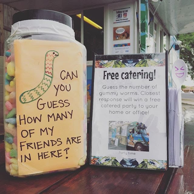 gummy worms in a jar with a sign telling people to guess how many are in the jar as a way of entering to win
