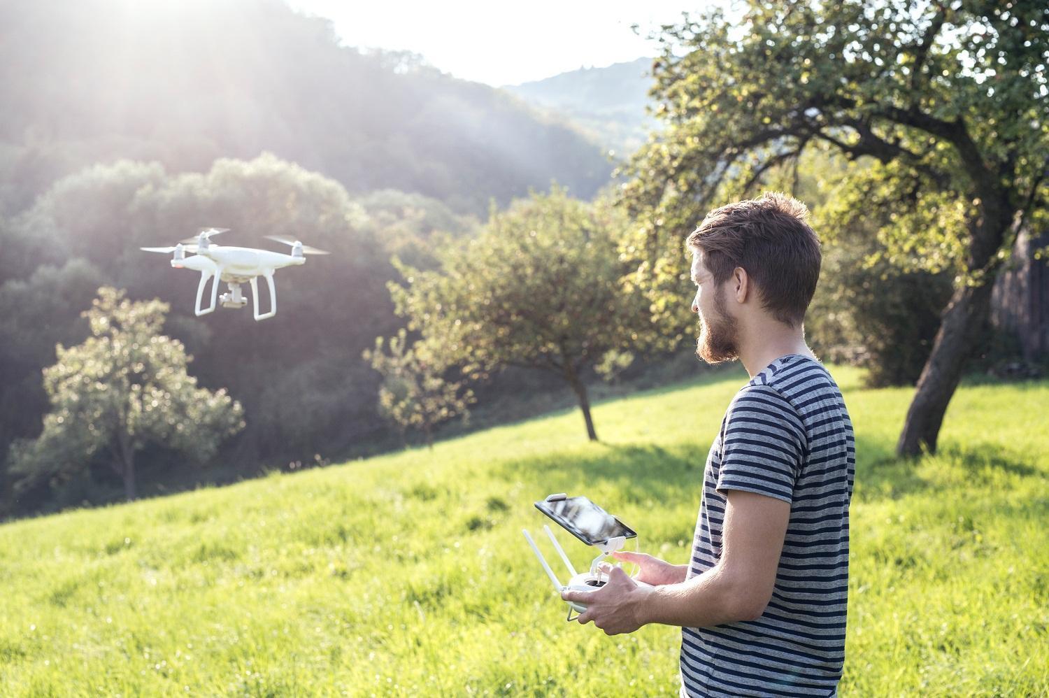 man-with-remote-control-and-flying-drone-with-camera.jpg