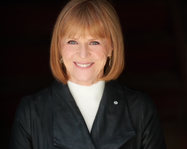 A head shot a Valerie Pringle wearing a white turtle neck and a leather jacket.