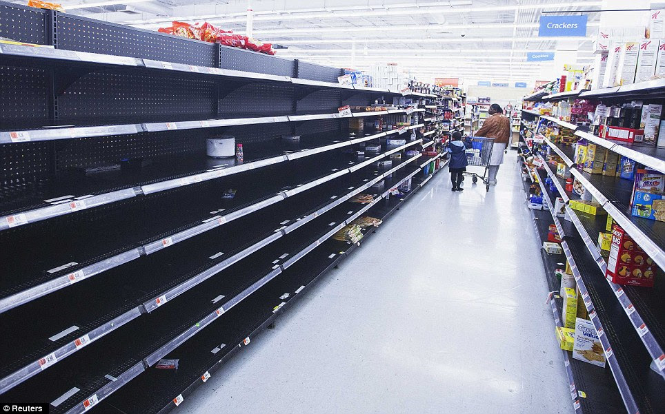 Empty shelves: A woman and child walk through an aisle, emptied in preparation for Hurricane Sandy, in a Wal-Mart store in Riverhead, New York, on Sunday