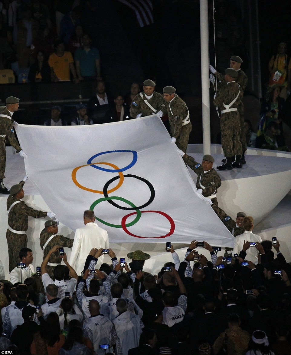 A bandeira olímpica foi levada para o palco no estádio e levantada por membros das forças armadas