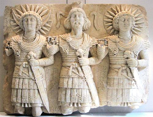 Ανάγλυφο με  τριάδα Παλμυρικών θεών χρονολογημένη περίπου το πρώτο μισό του πρώτου μεταχριστιανκού αιώνα. Στην μέση βρίσκεται ο μέγιστος θεός της Παλμύρας Bel φορώντας κάλαθο και διάδημα, στα δεξιά του ο θεός του φεγγαριού Aglibol και στα αριστερά του ο ηλιακός θεός Jarhibol. Η στρατιωτική εξάρτηση είναι Ελληνιστικού τύπου με πολλά Παρθικά ενδυματολογικά επιμέρους στοιχεία.Γενικά οι Θεοί των Αλεξανδρινών κέντρων φορούν ομοιόμορφους Ελληνιστικούς λινοθώρακες με ελασμάτινη ενίσχυση  κάτι που υπονοεί τυποποιημένη παραγωγή από κρατικά εργαστήρια. Η εξάρτηση λειτουργεί με αποτρεπτική σημασία καθώς επιδεικνύει την ετοιμότητά τους να υπερασπιστούν τις εκάστοτε Ελληνιστικές συγκεντρωτικές ηγεμονίες. Στην Ελληνιστική περίοδο οι Θεοί θα χάσουν οριστικά την Θεϊκή τους γύμνια που απολάμβαναν στην Κλασσική Αρχαιότητα. Ενδιαφέρον παρουσιάζει το γεγονός πως πριν την έλευση του Αλεξάνδρου στην Εγγύς Ανατολή οι ντόπιοι θεοί δεν εμφανίζονται με στρατιωτική περιβολή.