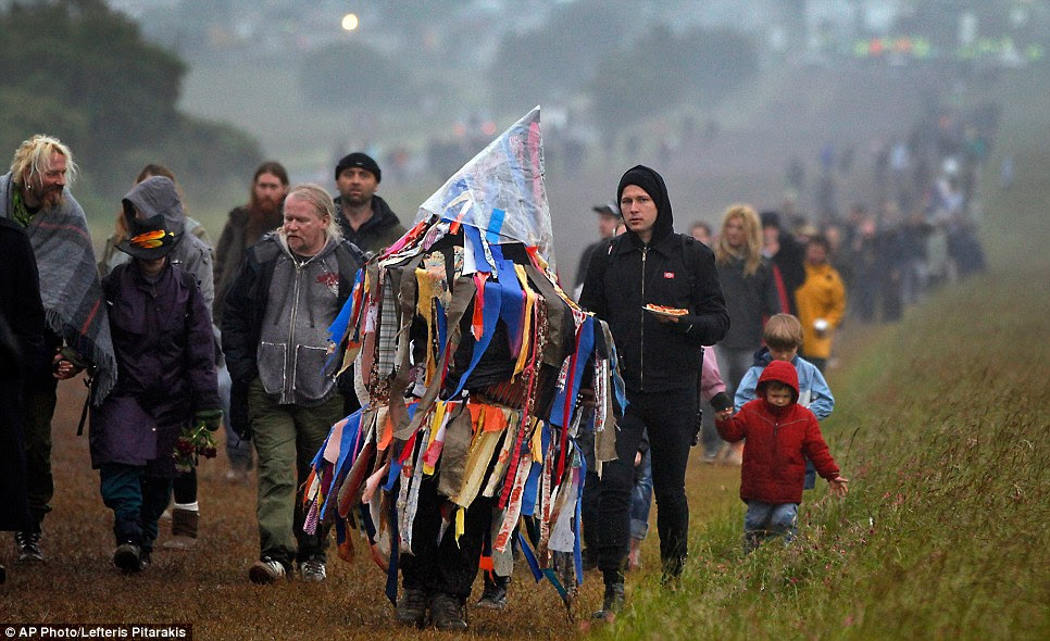 Until next time: A man playing an accordion beneath a costume of torn fabrics leaves Stonehenge