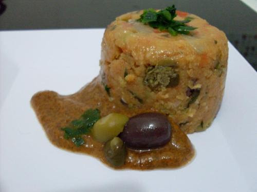 Cuscuz Paulista
Ingredientes:
6 colheres de sopa de azeite
1 cebola média
2 dentes de alho
3 tomates maduros picados
1/3 de xícara de extrato de tomate
100ml de leite de coco
4 colheres de sopa de cheiro verde picado
1/2 xícara de farinha de milho
1/2 xícara de farinha de mandioca
sal e pimenta a gosto
50g de azeitonas pretas picadas
50g de azeitonas verdes picadas
50g de alcaparras
Preparo:
Aqueça o azeite em uma panela, e refogue o alho e a cebola até dourar. Adicione os tomates picados, abaixe o fogo e deixe cozinhar por 10 minutos. Acrescente a polpa de tomate, o leite de coco e o cheiro verde. Salgue e polvilhe pimenta do reino. Deixe cozinhar em fogo baixo. Junte, aos poucos, a farinha de milho e a de mandioca. Continue mexendo constantemente até que a mistura comece a engrossar e a se desprender do fundo da panela. Desligue o fogo, junte as azeitonas e alcaparras e misture. Para modelar, umedeça a forma desejada em água corrente, despeje o cuscuz e cubra com filme plástico. Você pode enfeitar o cuscuz posicionando rodelas de tomate nas paredes da forma. Após esfriar, leve a geladeira por 3 horas. Desinforme sobre um prato. Decore com folhas de salsinha. Sirva frio.
Molho marinho
Ingredientes:
1 colher de azeite
1 folha de alga nori
2 dentes de alho descascados
suco de 1 limão
1 xícara de molho de tomate, pronto ou caseiro
Preparo:
Aqueça o azeite e refogue a alga nori picada para murchar um pouco. Adicione os dentes de alho e uma pitada de sal. Bata o refogado no liquidificador com o molho de tomate e o limão até homogeneizar. Sirva frio, acompanhando o cuscuz.