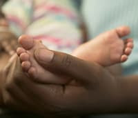 Photo: A hand holding the foot of a premature baby.