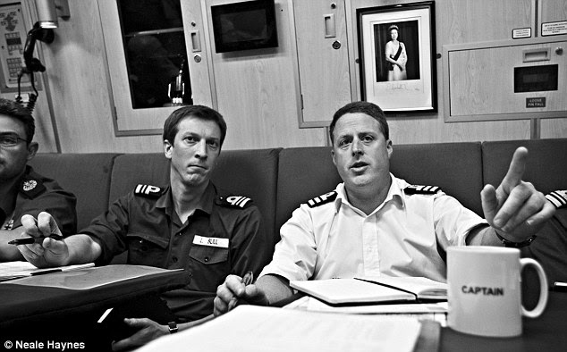 Commander Asquith (on right) and Lieutenant Commander Bull in the wardroom on HMS Talent under a portrait of the Queen