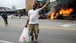 A man carries items from a store as police vehicles
