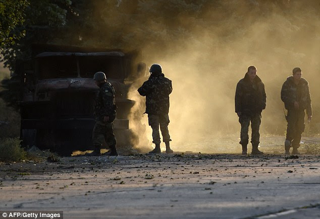 Ukrainian army soldiers check a burnt army truck after an overnight bombing attack at an Ukrainian army checkpoint in the outskirts  of Mariupol