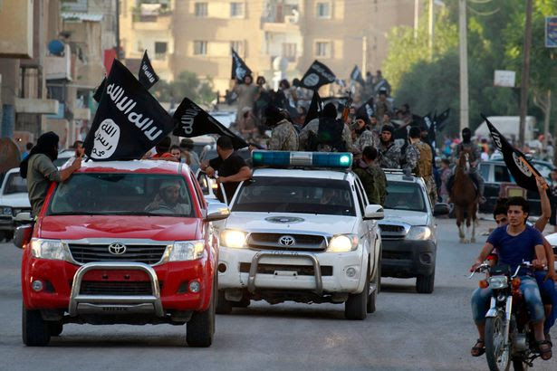 Militant Islamist fighters waving flags, travel in vehicles as they take part in a military parade along the streets of Syria's northern Raqqa province June 30, 2014