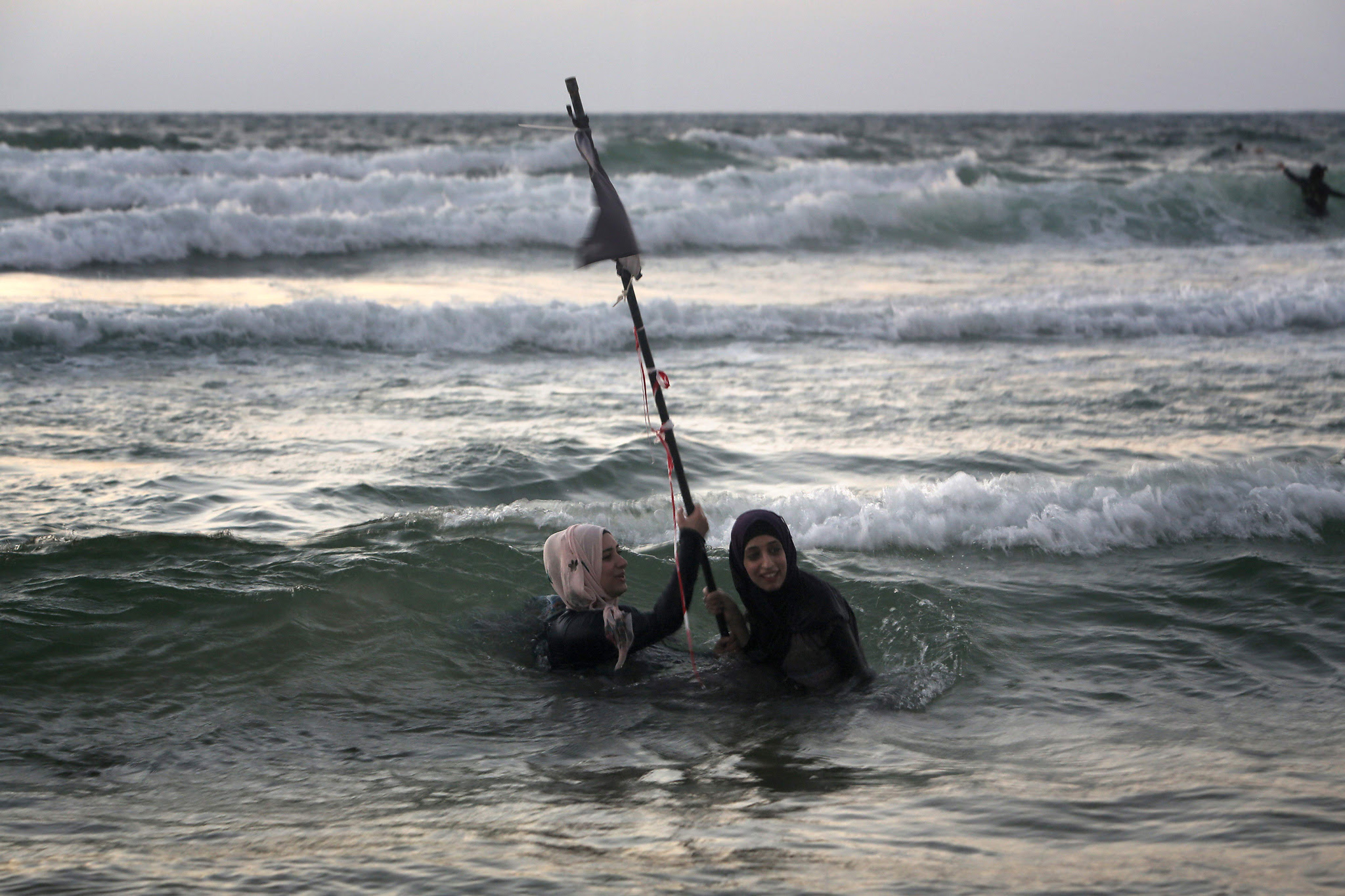 Palestinian women swim in the Mediterranean sea on the beach in Tel Aviv during the Eid al-Adha holiday