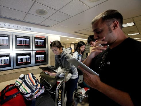 American Airlines passengers use their tablets while waiting for flights at Los Angeles International Airport on April 16, 2013.