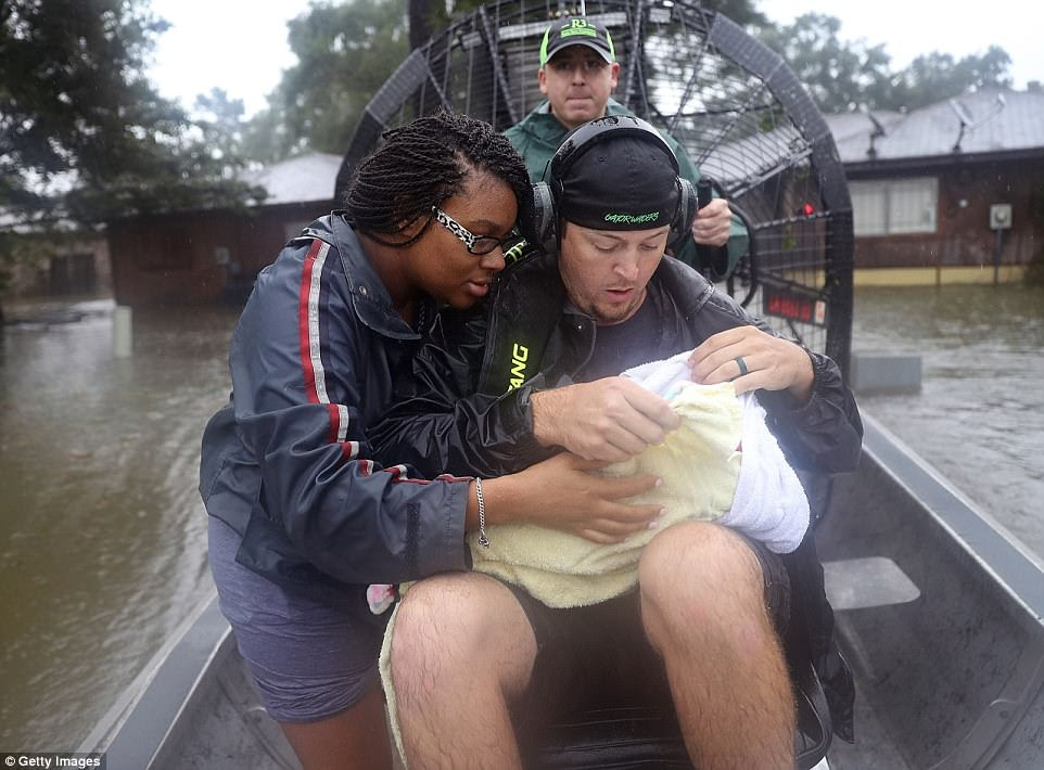 New mother Shardea Harrison watches over her three-week-old baby as she is rescued from her home by Dean Mize and Jason Legnon 