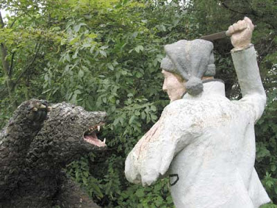 Close up of a sculpture showing a man attacking a bear with a knife, concrete