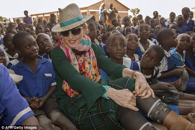 Madonna senta-se entre crianças de Malawian durante uma visita à escola preliminar de Mkoko em 2014