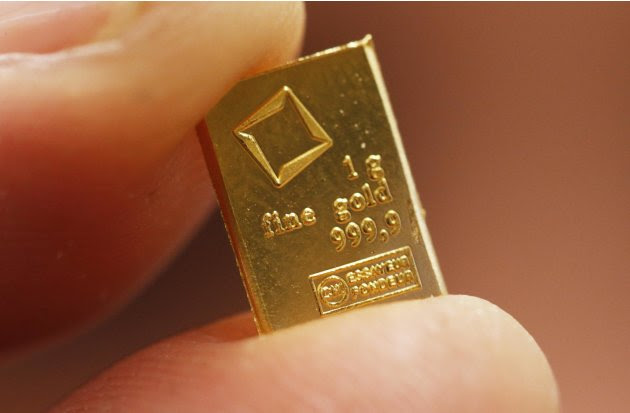An employee shows a 1 gram piece of a gold Combibar at a plant of gold refiner and bar manufacturer Valcambi SA in the southern Swiss town of Balerna