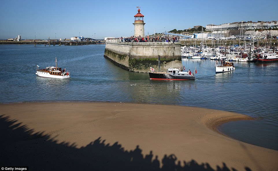 The shadows of hundreds of people are seen on the shore as the fleet makes its way past the harbour walls in Ramsgate, Kent