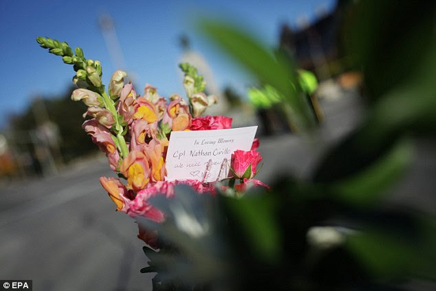 Remembered: Flowers with a card sit at the foot of the War Memorial in Ottawa on Thursday