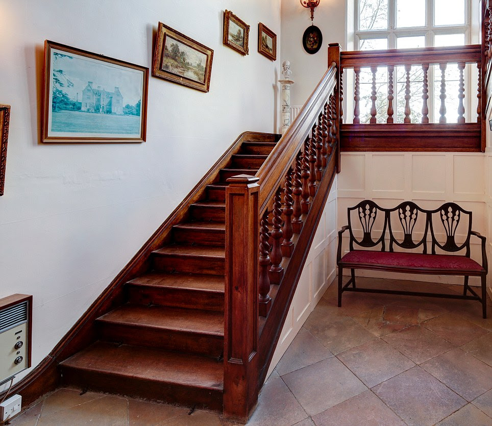 The property features many original features including this carved wooden staircase; a window half-way up provides a perfect spot to look out over the grounds