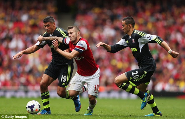 Falling down: Jack Wilshere goes between Jonathan Walters and Geoff Cameron