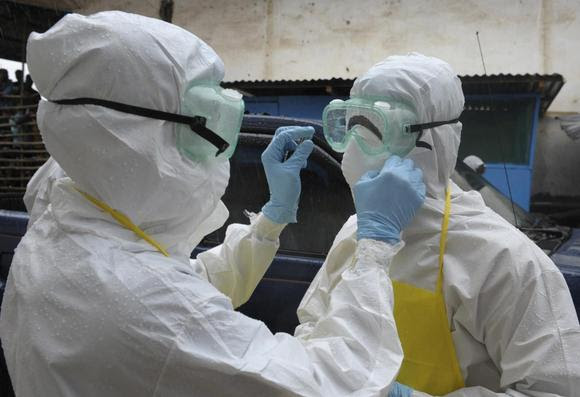 Os profissionais de saúde vestindo roupas de proteção preparar-se antes de realizar um cadáver abandonado apresentando sintomas do Ebola no mercado Duwala em Monrovia 17 de agosto de 2014 REUTERS / 2Tango