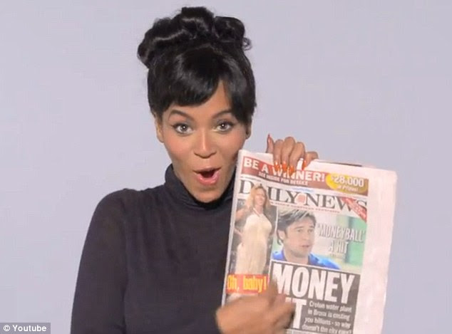 Olha, sou eu! Segurando um exemplar do The New York Daily News, Beyonce aponta para uma imagem do tapete vermelho de si mesma na capa, em que sua barriga está em exposição em um longo vestido elegante