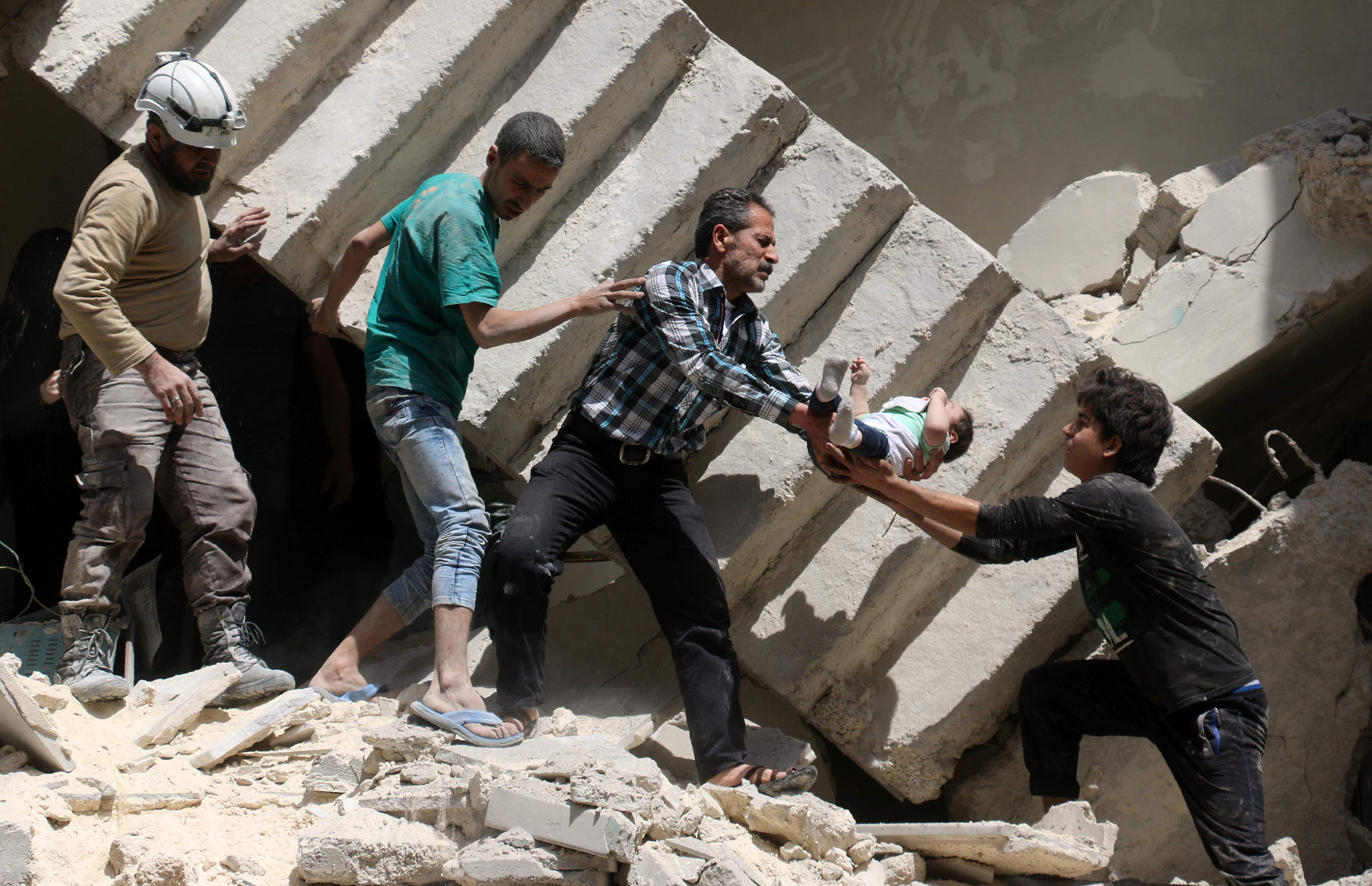 Syrian civil defence volunteers and rescuers remove a baby from under the rubble of a destroyed building following a reported air strike on the rebel-held neighbourhood of al-Kalasa in the northern Syrian city of Aleppo.
