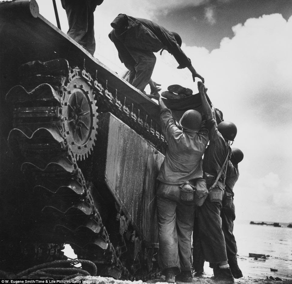 Hoisted to safety: In a photograph taken in Guam, a wounded American Marine is loaded onto an 'alligator' tracked amphibious vehicle for evacuation during fighting against Japanese troops