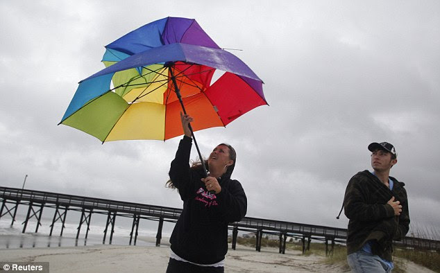 Up close and personal: Christy Deal of Whiteville, North Carolina, tries to hold on to an umbrella as her son Cage looks on during a trip to see Hurricane Sandy as it causes high surf and winds in Ocean Isle Beach