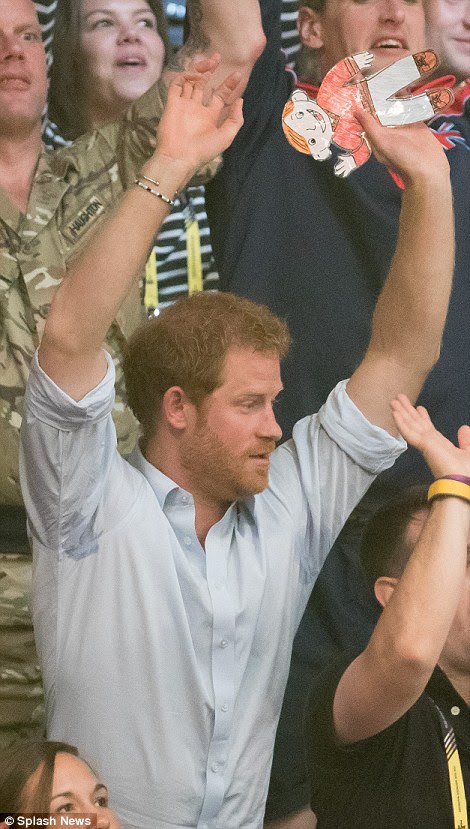The Royal appeared to be holding a child-drawn, laminated figure in his left hand as he threw his hands into the air