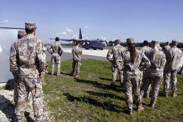 American soldiers watch a US Air Force C-130 during NATO's Steadfast Javelin II military exercise