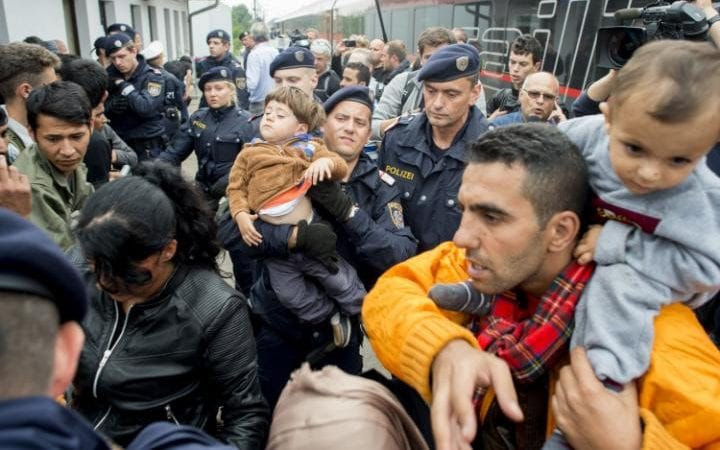 Austrian policemen and migrants in the Austrian village of Nickelsdorf on September 5, 2015. Thousands of migrants streamed into Austria from Hungary, in what Vienna called a "wake up call" for Europe to get to grips with its biggest refugee influx since World War II.