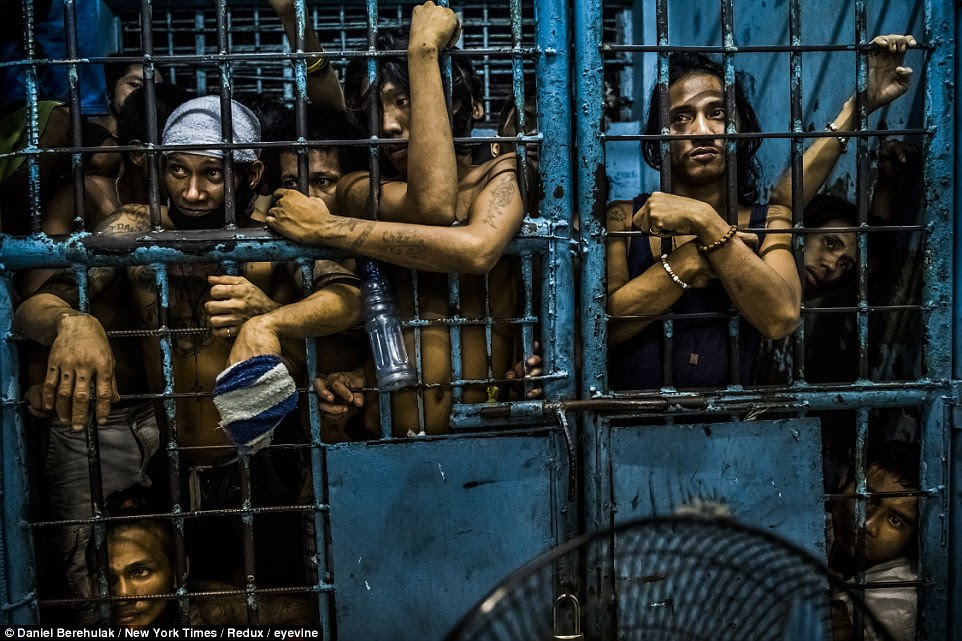 Inmates at a Manila police station watch as drug suspects are processed after their arrests in the Philippines