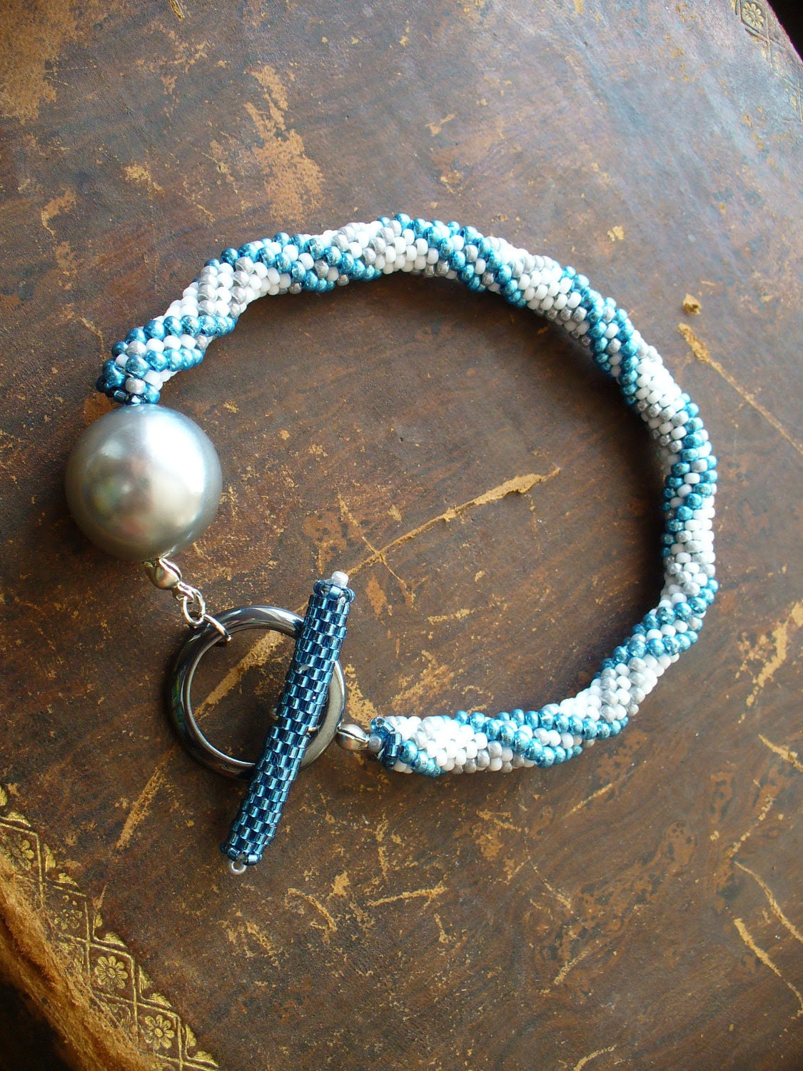 Bead Crochet Rope Bracelet with pearl-grey and metallic-blue stripes on white ground and unique Toggle-clasp - DianaCoe