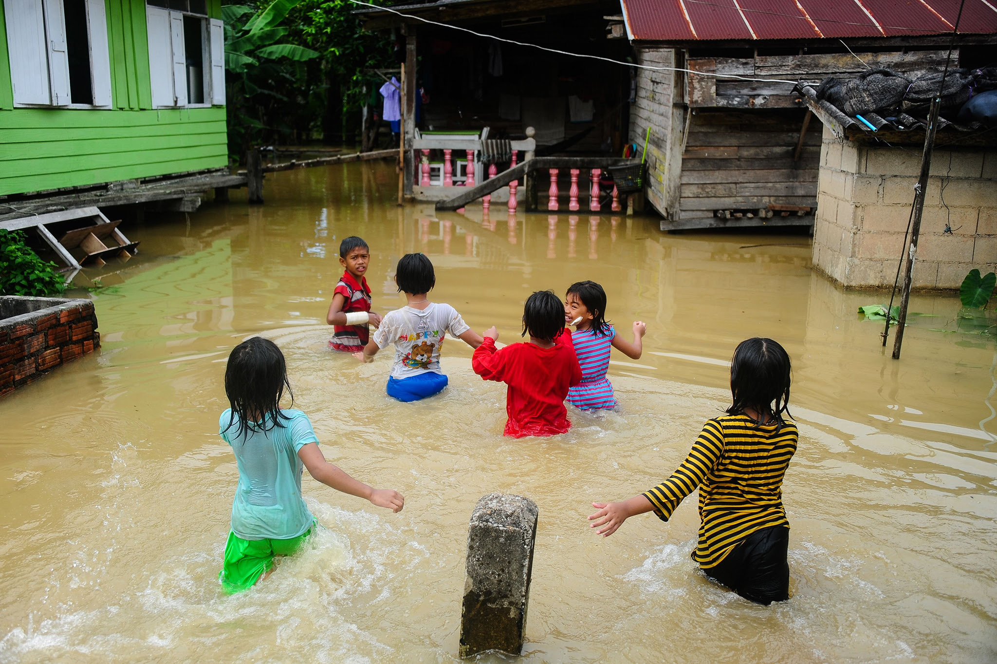 Children play near houses inundated by floodwaters after heavy rains in the Rangae district of the southern province of Narathiwat on December 21, 2016. / AFP PHOTO / MADAREE TOHLALAMADAREE TOHLALA/AFP/Getty Images