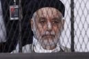Baghdadi al-Mahmoudi, who was the last prime minister of Gaddafi's government, sits behind bars during the second hearing in his trial at a prison facility in Tripol
