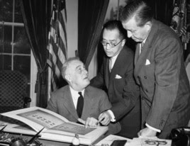 1941年10月10日，中国驻美大使胡适博士（中）向美国总统罗斯福（左）解说含有中国一万师生签名的书册