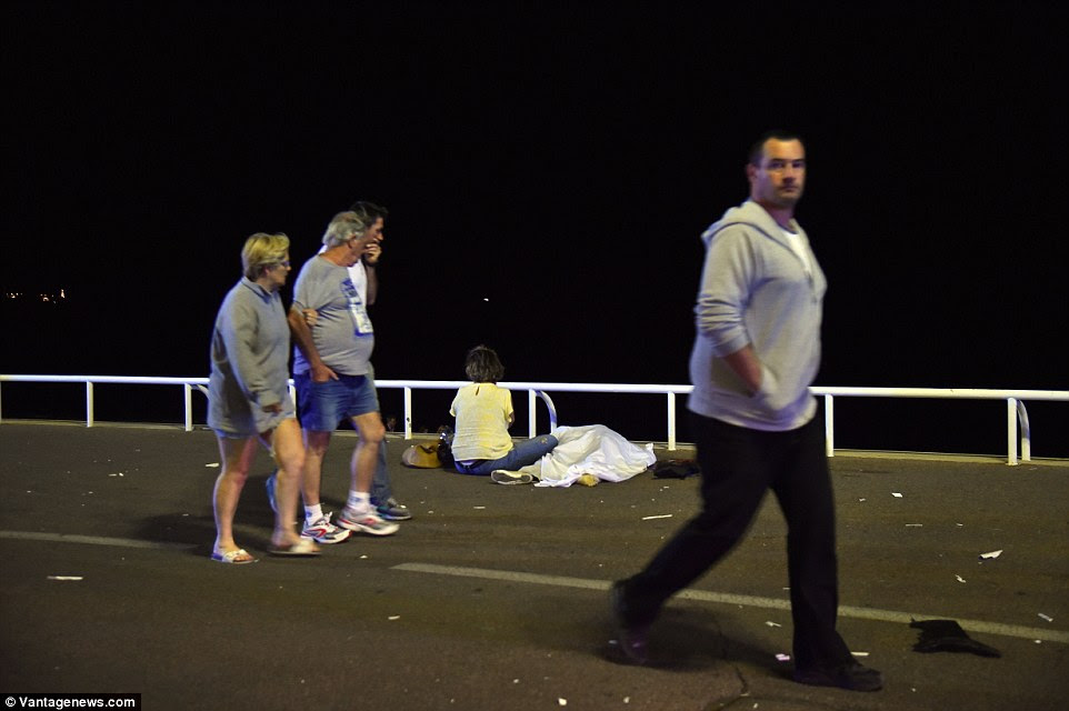 Tragédia: Uma família de turistas olhar para uma mulher em amarelo enquanto se senta ao lado do corpo de um ente querido, morto no ataque terrorista