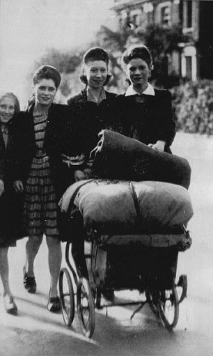 A family wheel all their bedding in a pram, as they make their way to an air raid shelter where they will spend the night