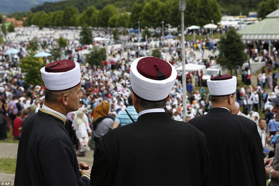 Bosnian Muslim clerics watch the funeral in Srebrenica, Bosnia on Friday July 11, 2014. The eastern, Muslim-majority town of Srebrenica was a U.N.-protected area besieged by Serb forces throughout Bosnia's 1992-95 war. But U.N. troops offered no resistance when the Serbs overran the town, rounding up the Muslims and killing the males. An international court later labeled the slayings as genocide. (AP Photo/Amel Emric)