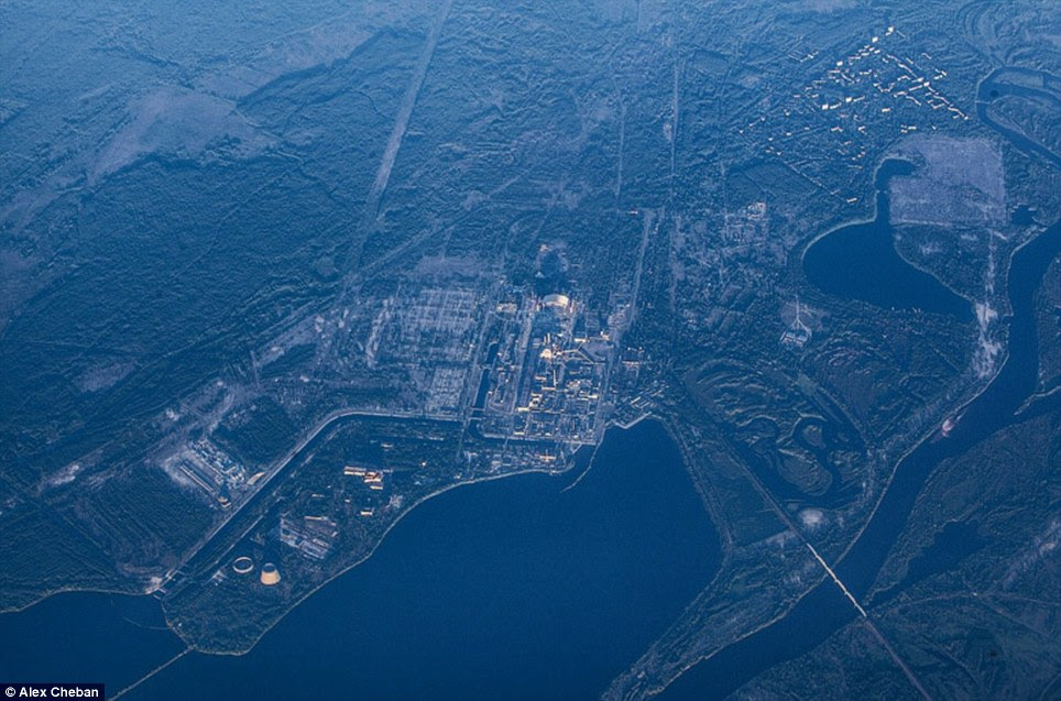 Eerie: This picture shows the city of Pripyat, top right, and the Chernobyl power plant, centre surrounded by the forest