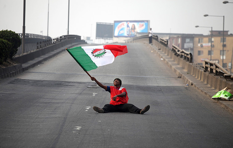Nigeria fuel protests: A protester waves a flag on an empty road
