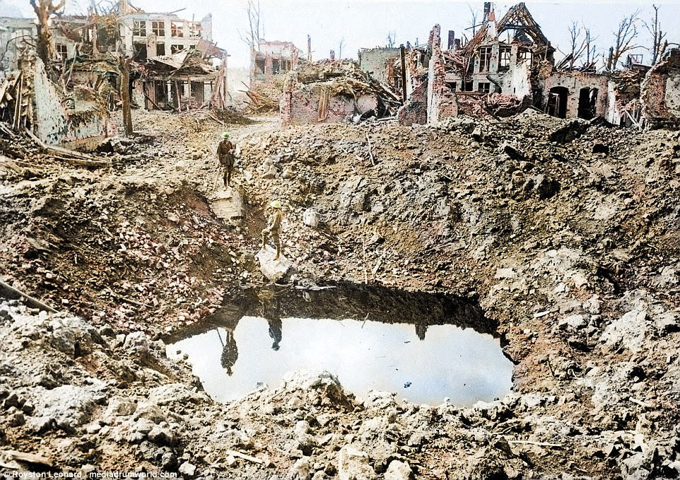 Destruction: This photo shows a bombed out town with collapsing buildings as a lone soldier wanders near a crater. Pictured 24. A gigantic shell crater, 75 yards in circumference, Ypres, Belgium, October 1917