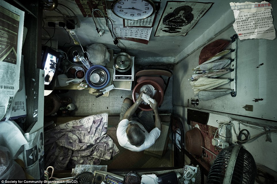 Utility room: A man washes his clothes while sitting on his bed next to his 'kitchen'. Hundreds of thousands of people still live in caged homes like this in Hong Kong