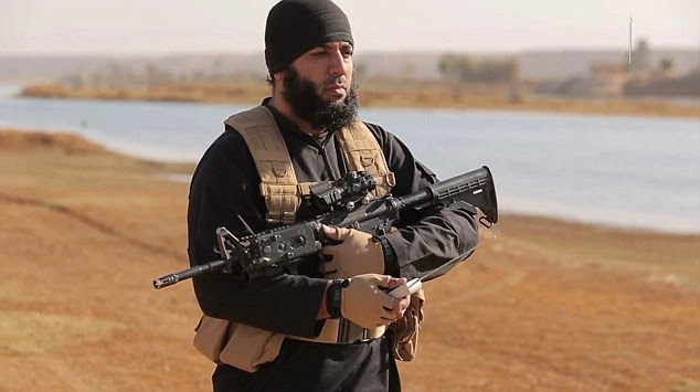 The ISIS thug, dressed in black clothes and wearing a suicide vest, ignites the fire using a detonator as he carries an assault rifle