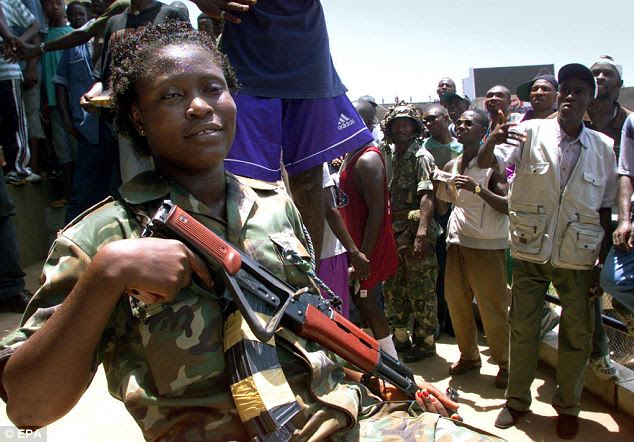A woman soldier poses with her gun during a rally in a stadium in Freetown, Sierra Leone: Women have classically been presented as the victims of war, or alternatively as supporting men from behind the lines or on the 'home front'